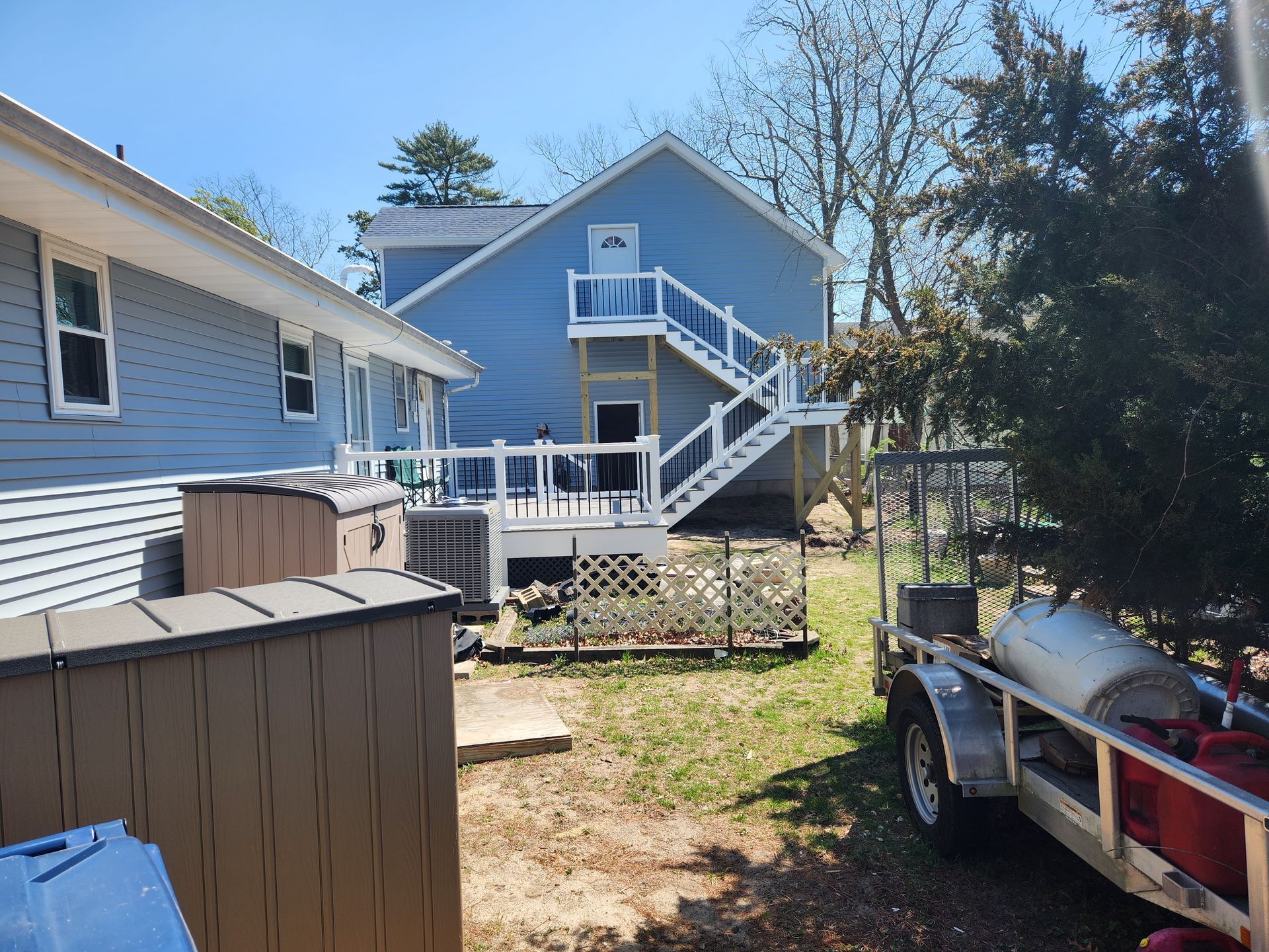 A trailer is parked in front of a house with stairs.