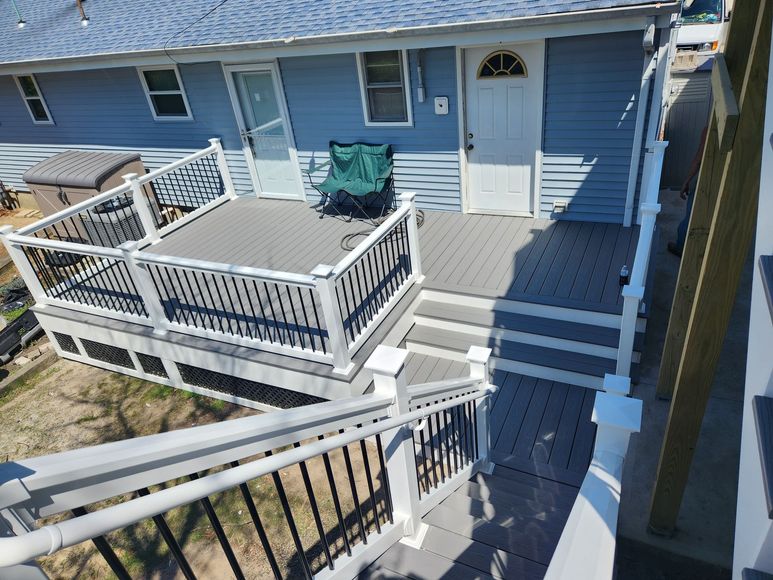 A blue house with a large deck and stairs leading to it.