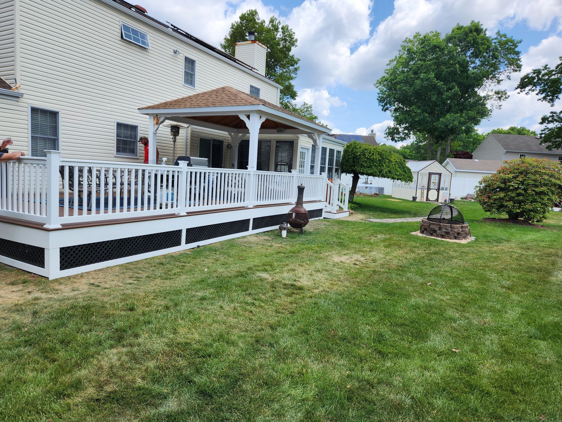 A white house with a large deck in the backyard.