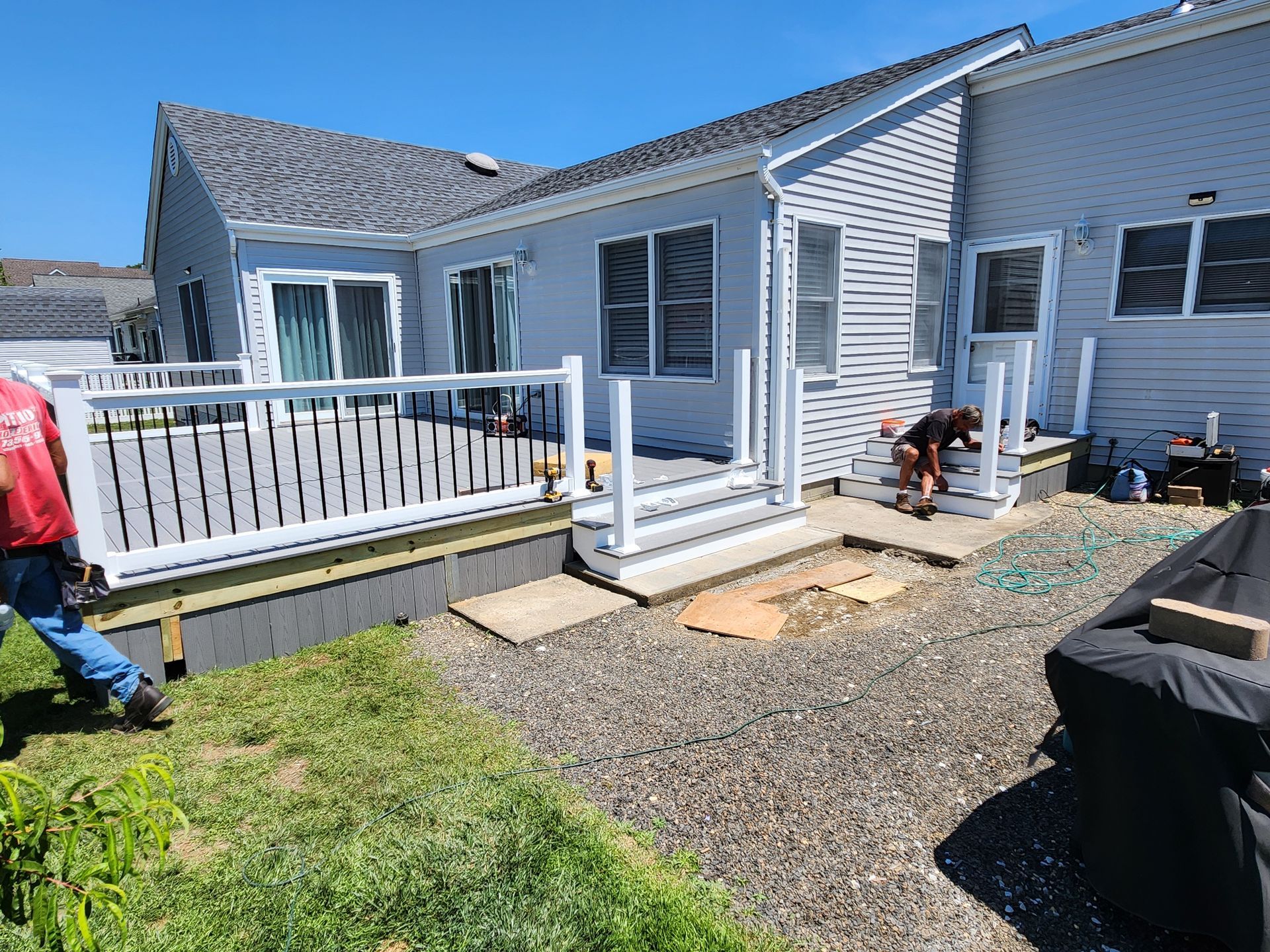 A man is working on a deck in front of a house.
