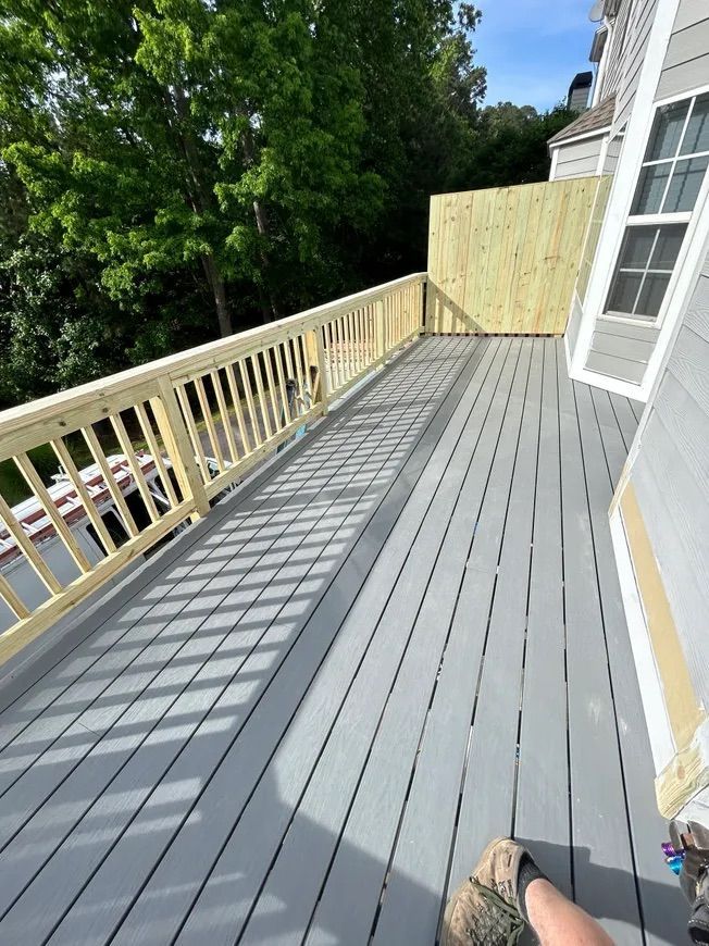 A newly built gray deck with a wooden railing.