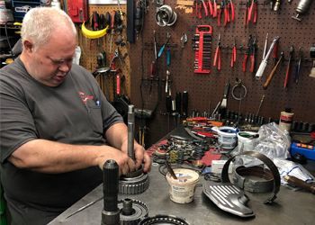 A man is working on a gearbox in a garage.