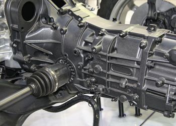 A close up of a car engine with a gearbox on display.