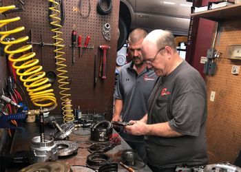 Two men are working on a car in a garage.