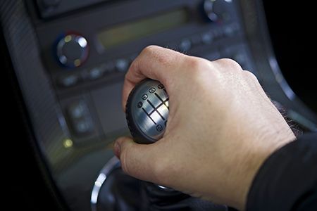 A close up of a person 's hand holding a gear shift in a car.