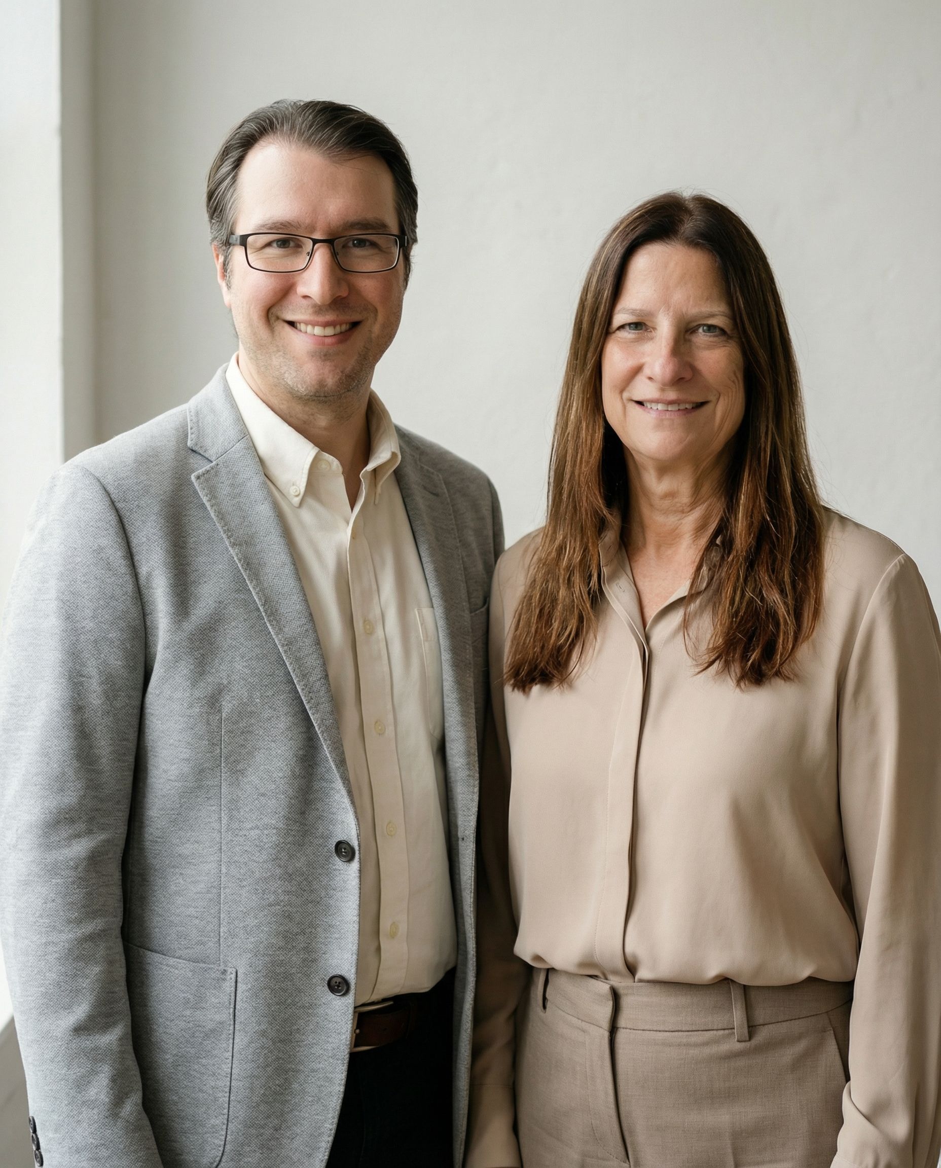 Woman with brown hair, smiling, in a green jacket and white shirt indoors, hallway background with plants.