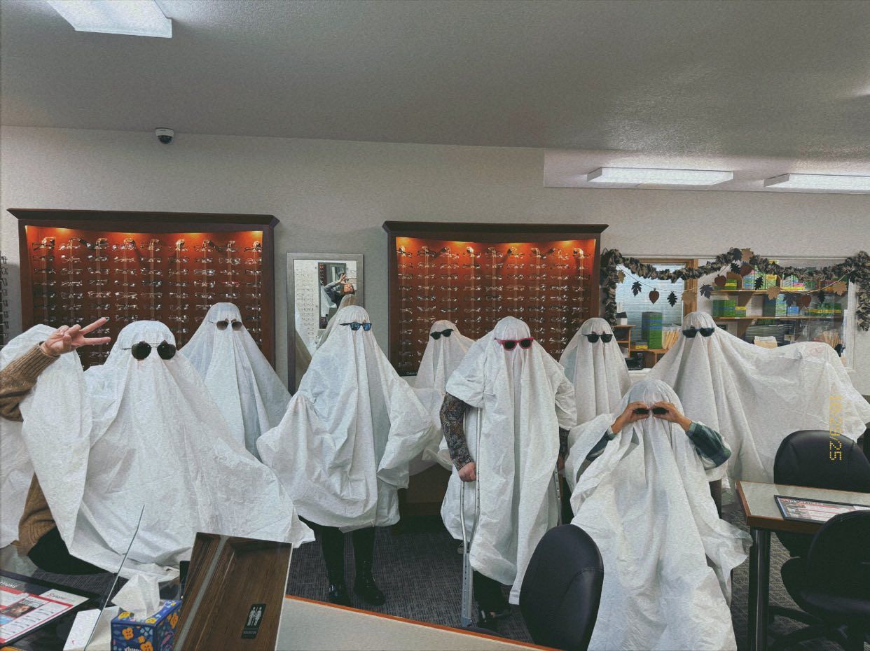 Group of people dressed as ghosts wearing sunglasses in an optical store.