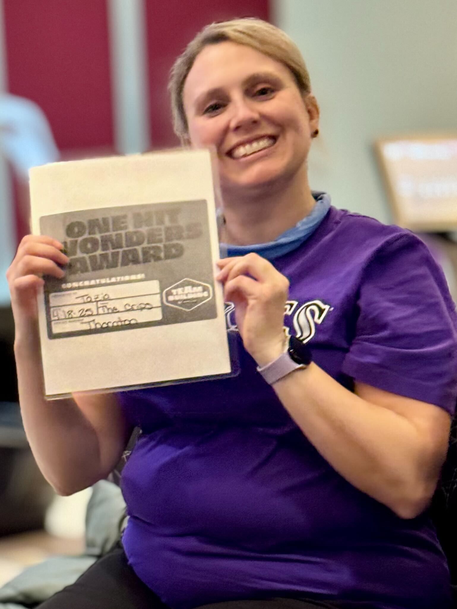Woman in purple shirt smiling, holding 