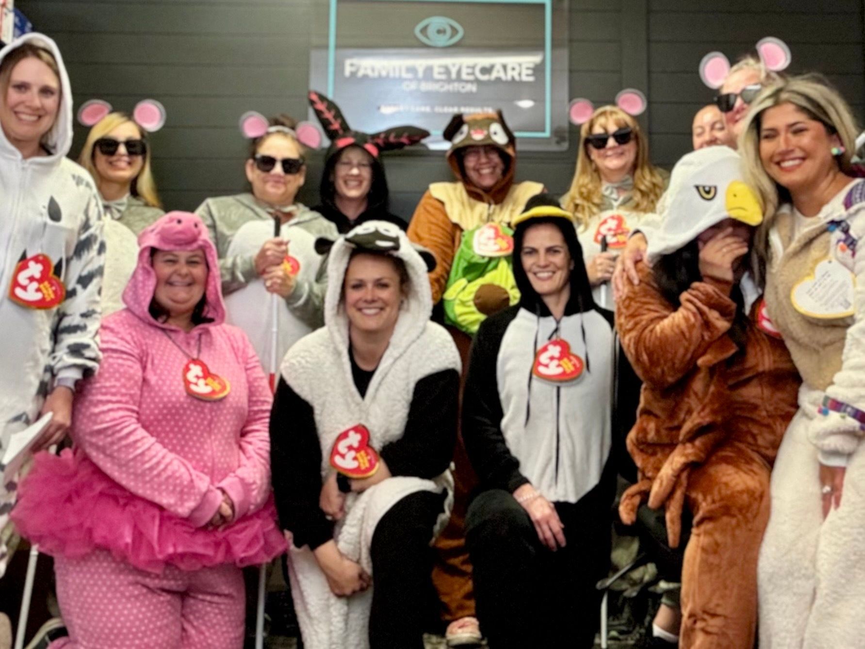 Group of people in animal onesie costumes in front of an eye care office.