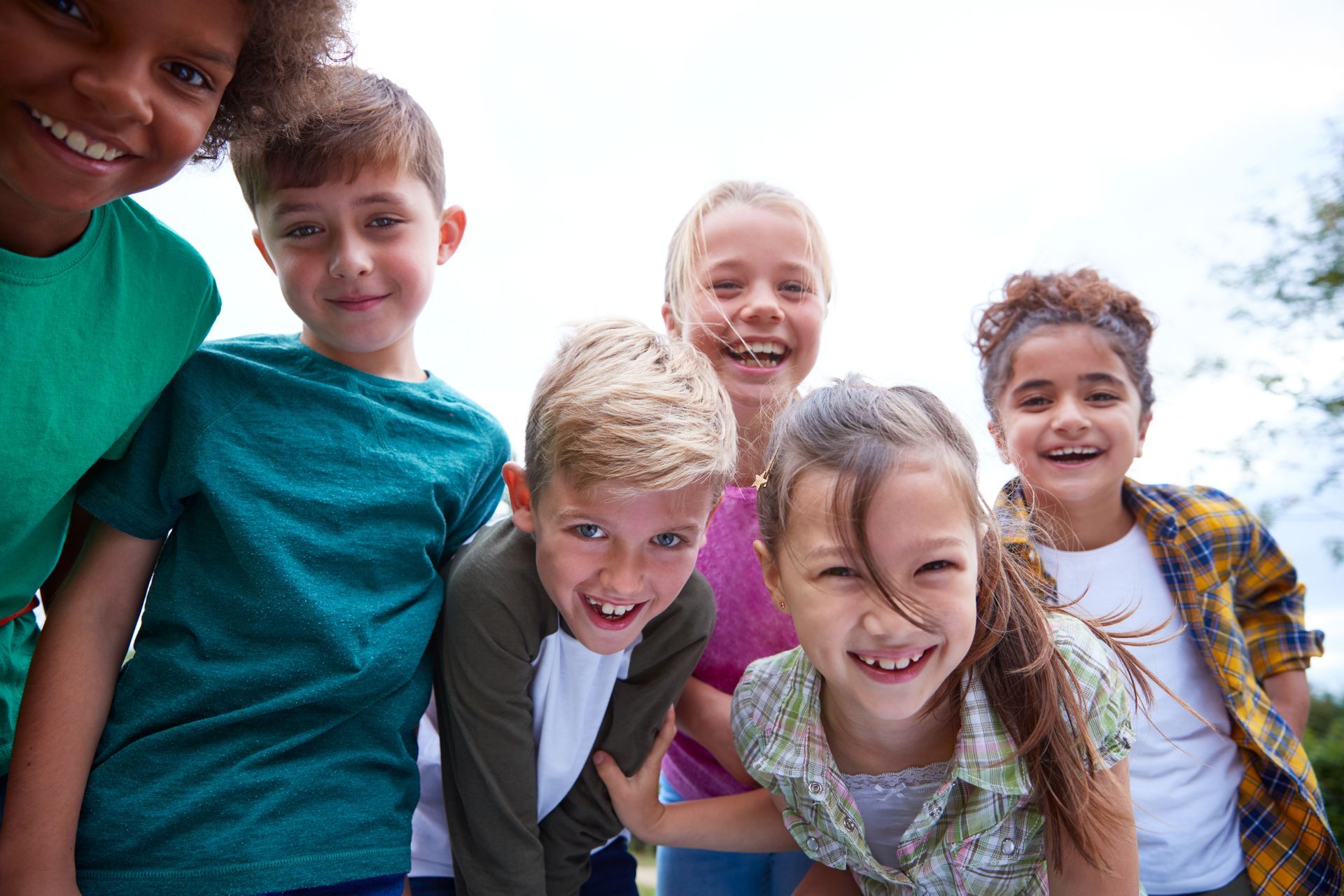 Group of smiling children looking towards the camera, outdoors.