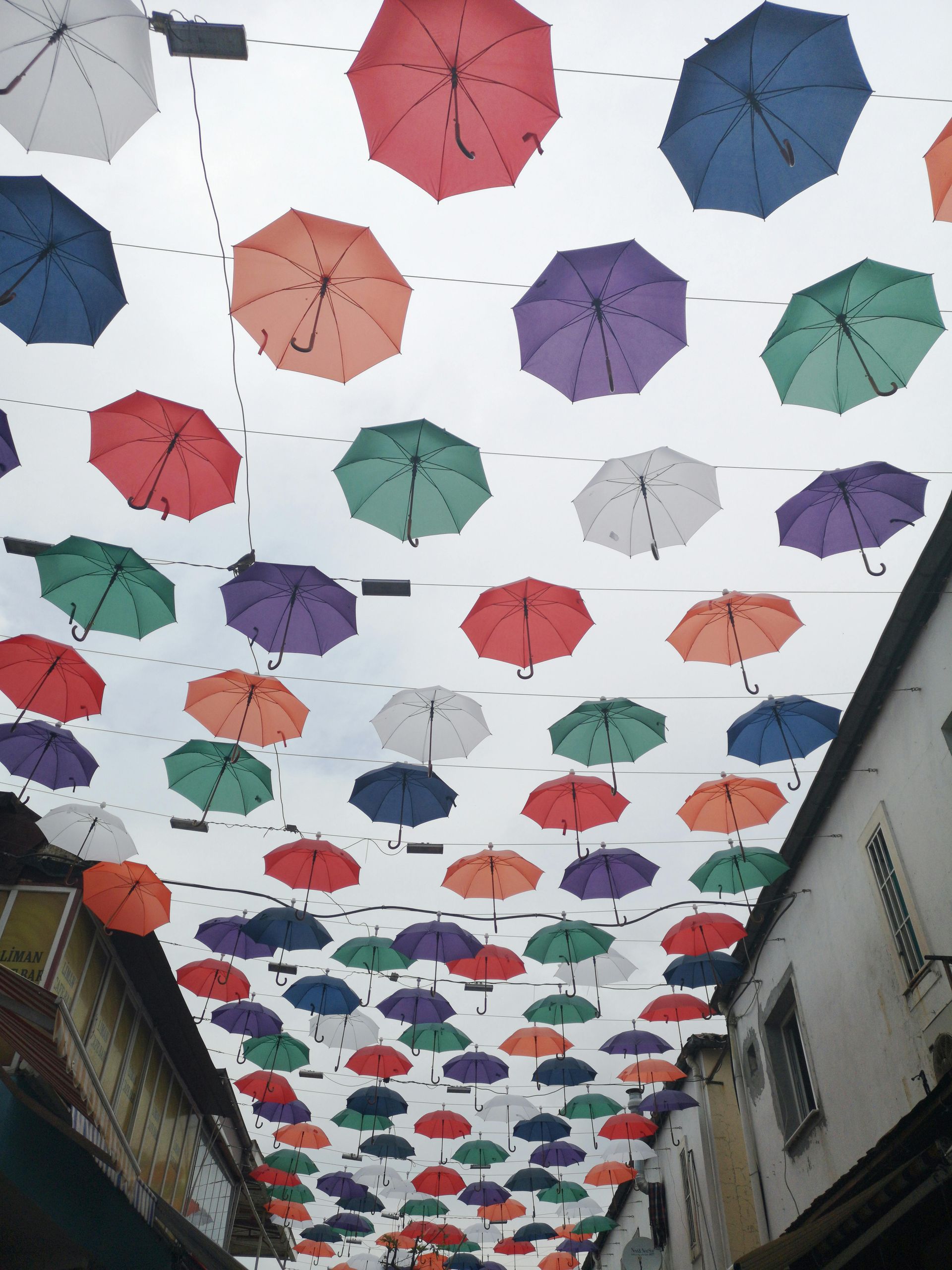 Colorful umbrellas suspended above a narrow street, creating a canopy.