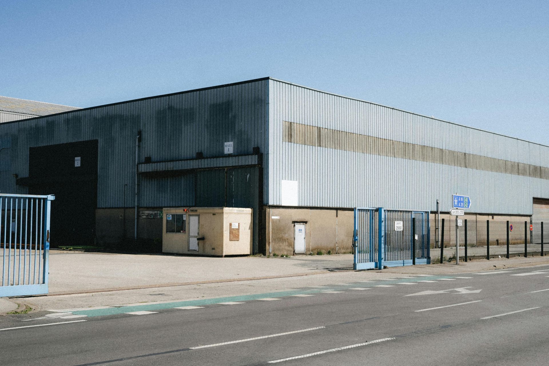 Person driving a car, holding the steering wheel, wearing a red and blue plaid shirt.