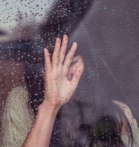 woman leaning against rainy window