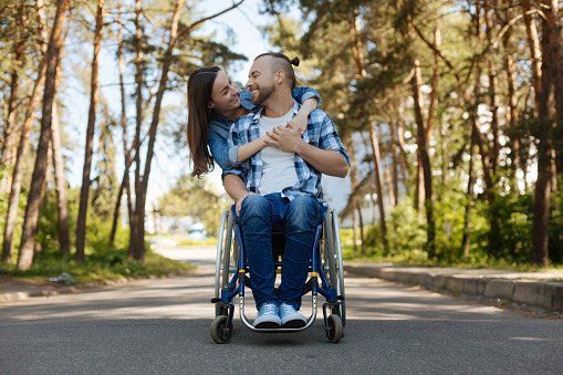 man with wheelchair hugging a woman