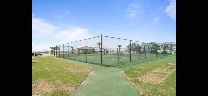 There is a tennis court with a fence around it.