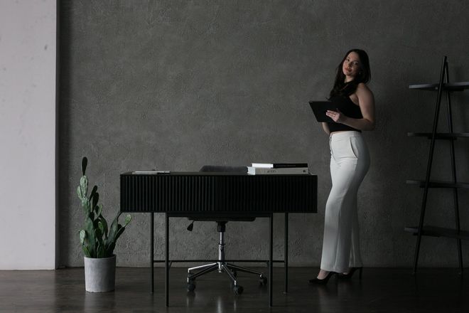 2 women dressed in black top and white pants discussing something