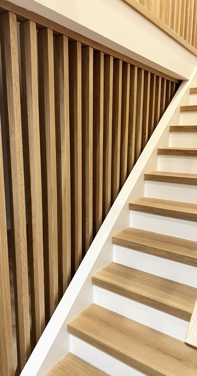 A staircase featuring wooden treads, white risers, and a slatted wood railing.