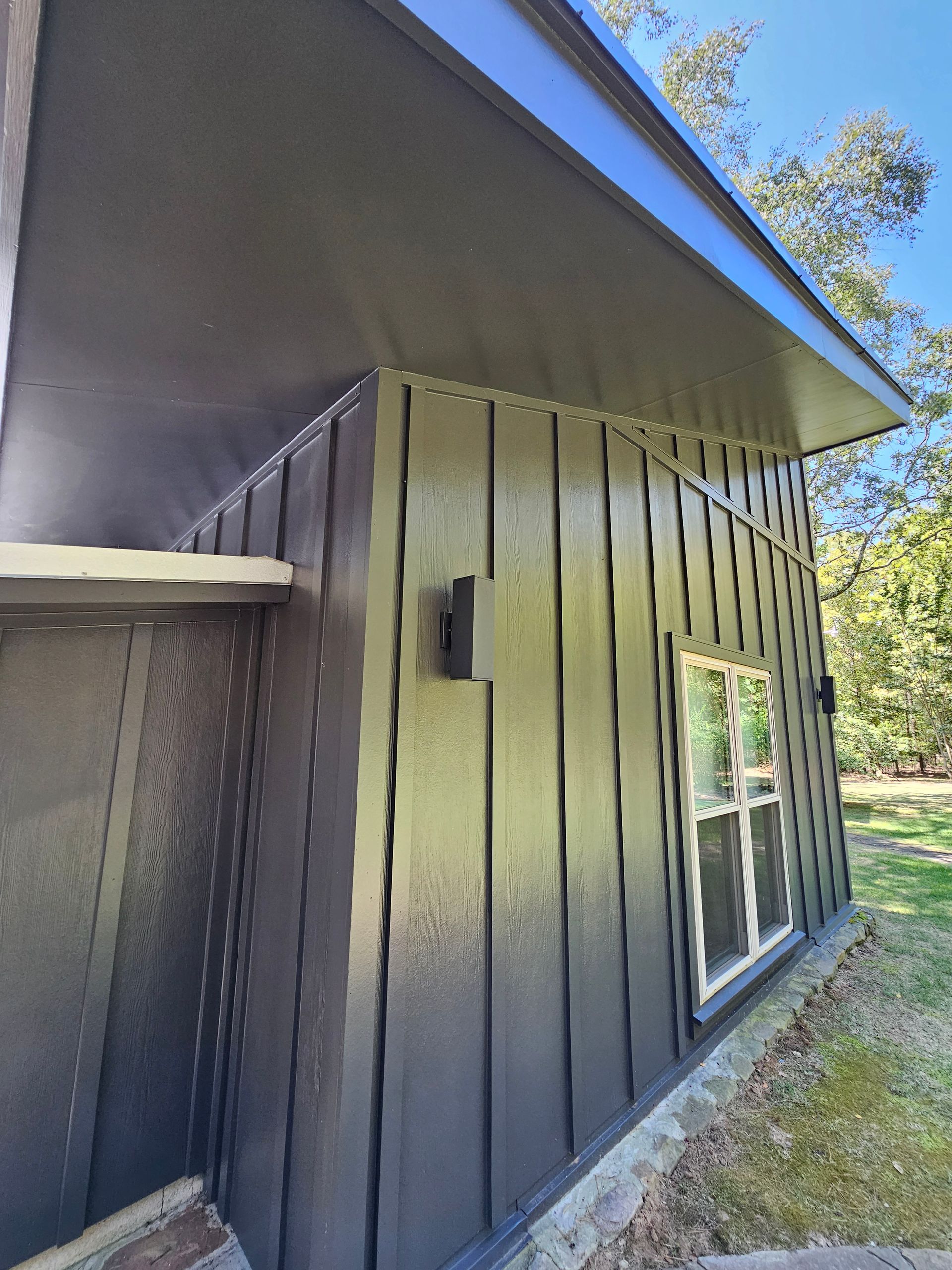 A black house with a blue roof and a window.