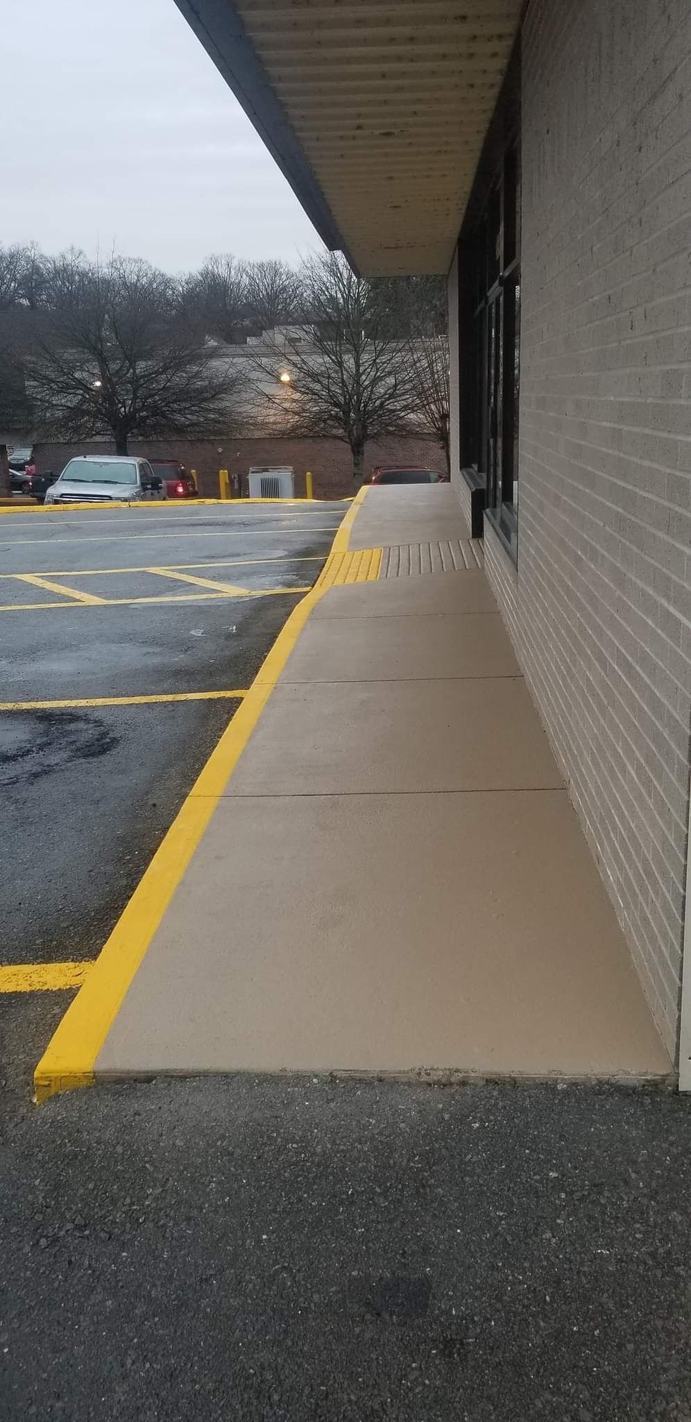 A sidewalk leading to a parking lot next to a building.