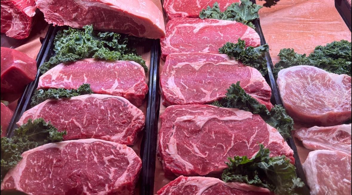 There are many different types of meat on display in a butcher shop.