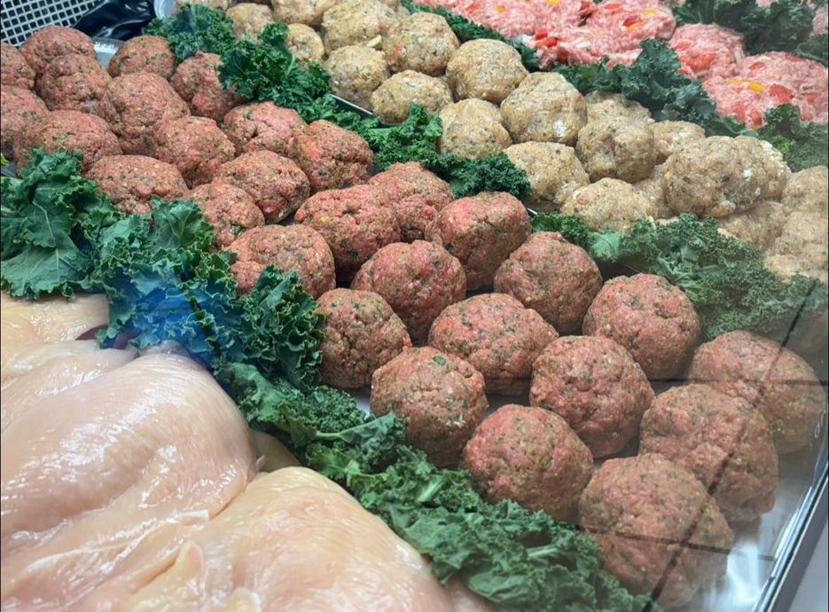 A display case filled with meatballs and chicken breasts.