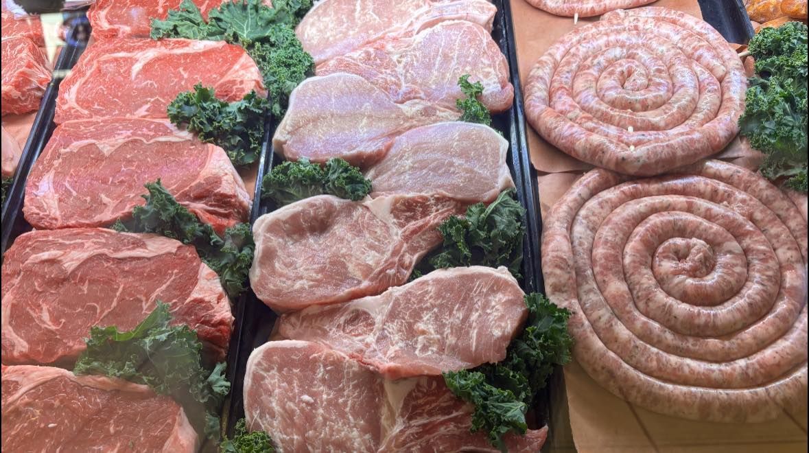 A variety of meats and sausages are on display at a butcher shop.