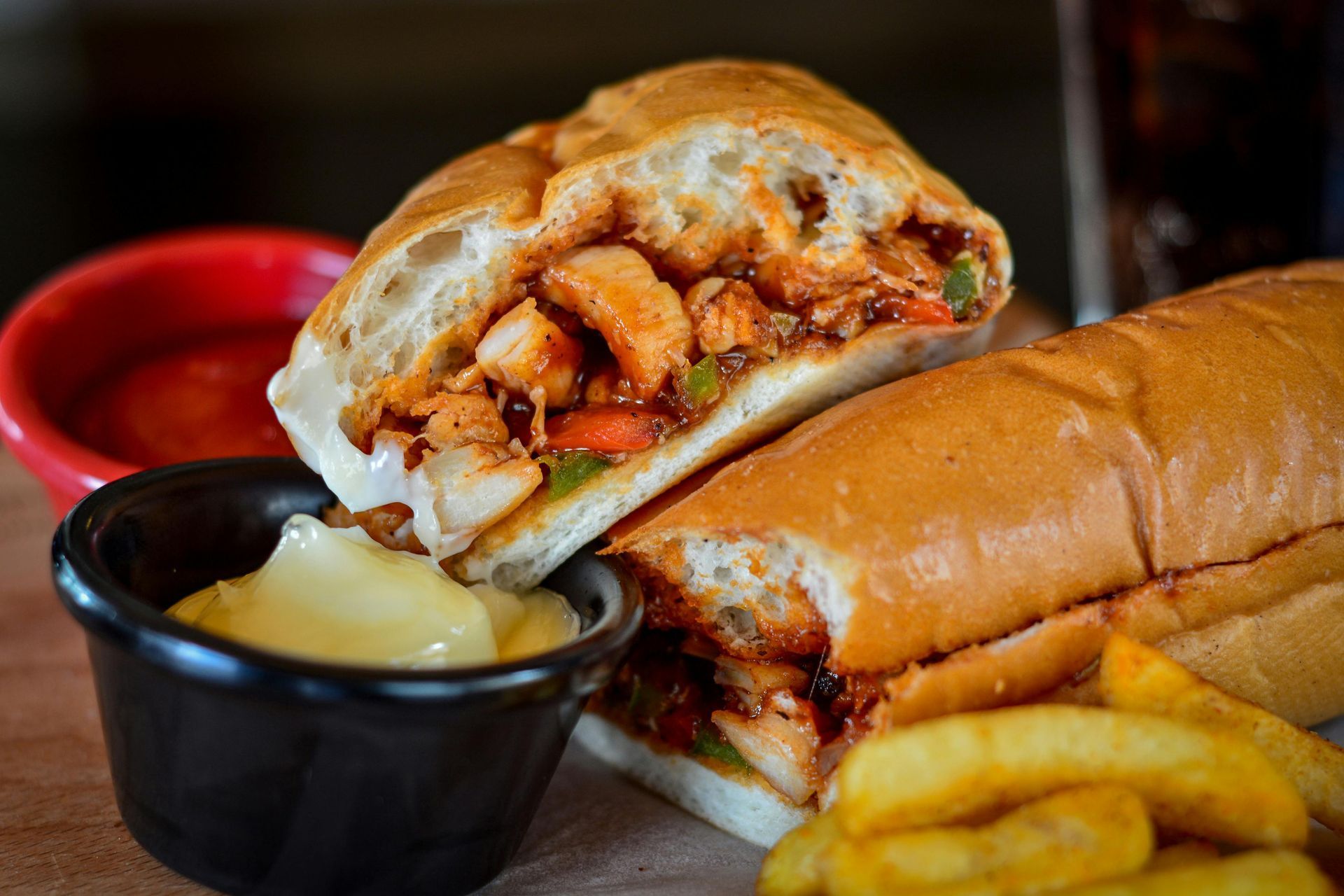 A sub sandwich with french fries and ketchup on a table.