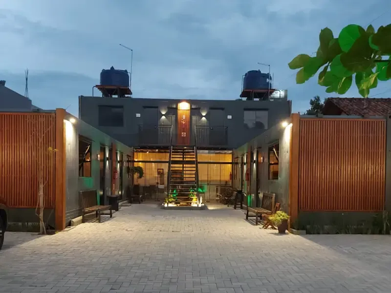 Prédio moderno com design simétrico, iluminado ao entardecer. Dois reservatórios de água no telhado. Tons de cinza e marrom.