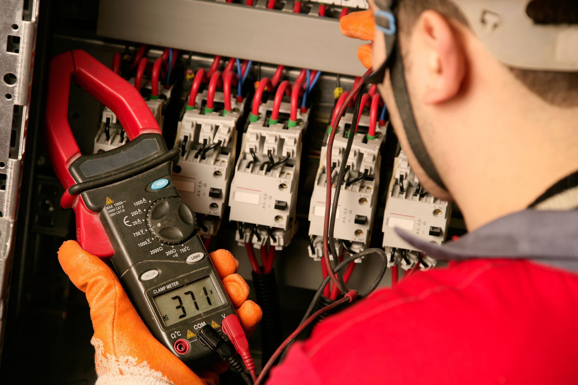 A man is using a multimeter to test an electrical outlet.