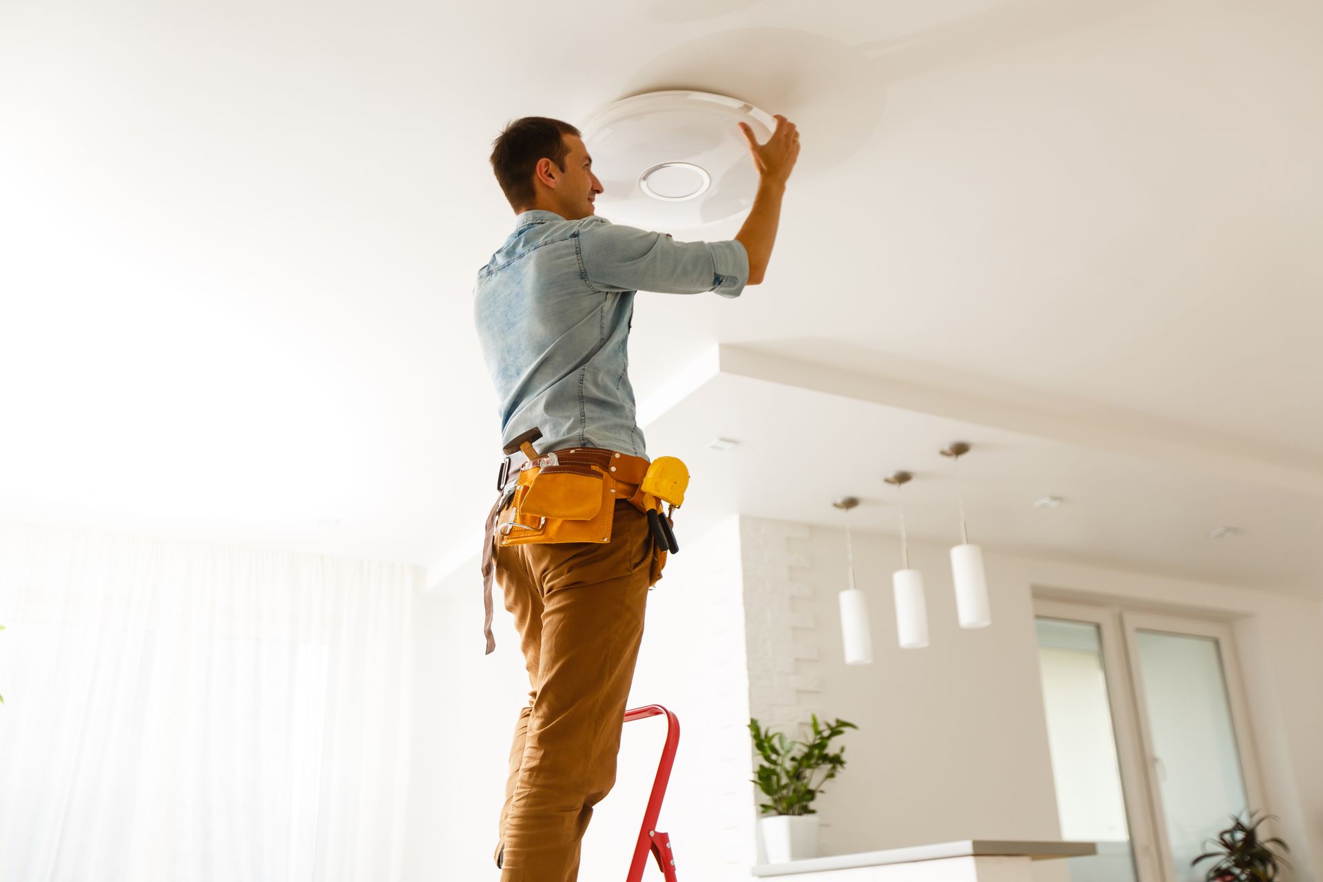 Professional electrician installing kitchen lights, showcasing expert electrical services.