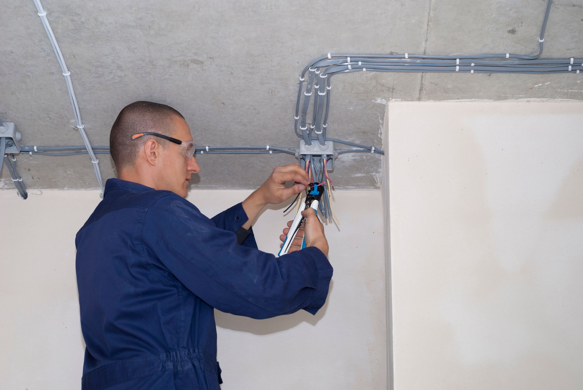 A man in a blue uniform is working on a ceiling.