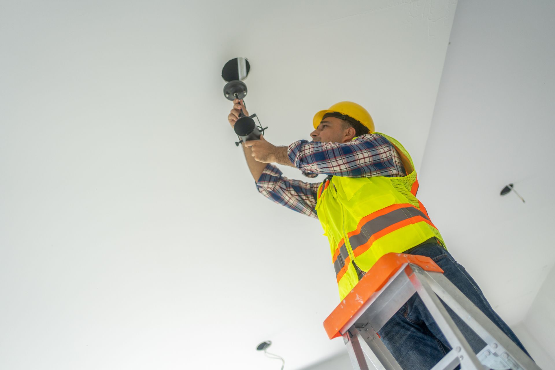 View from the ground up of a geared electrician working on a lightbulb.
