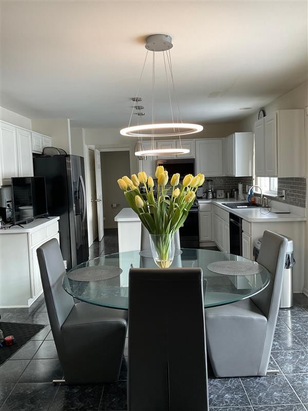 Kitchen with round glass table, gray chairs, white cabinets, and yellow tulips.