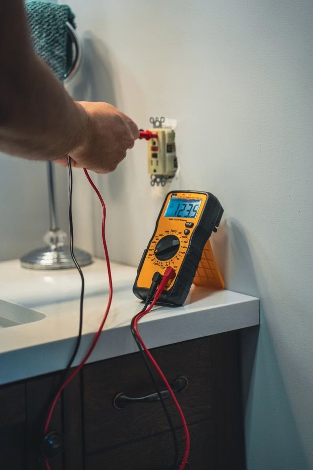 A man is installing a light switch on a wall with a screwdriver.