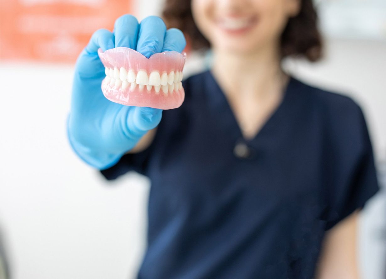 Dentist holding denture | Ringwood, VIC | Abstract Arch Denture Clinic