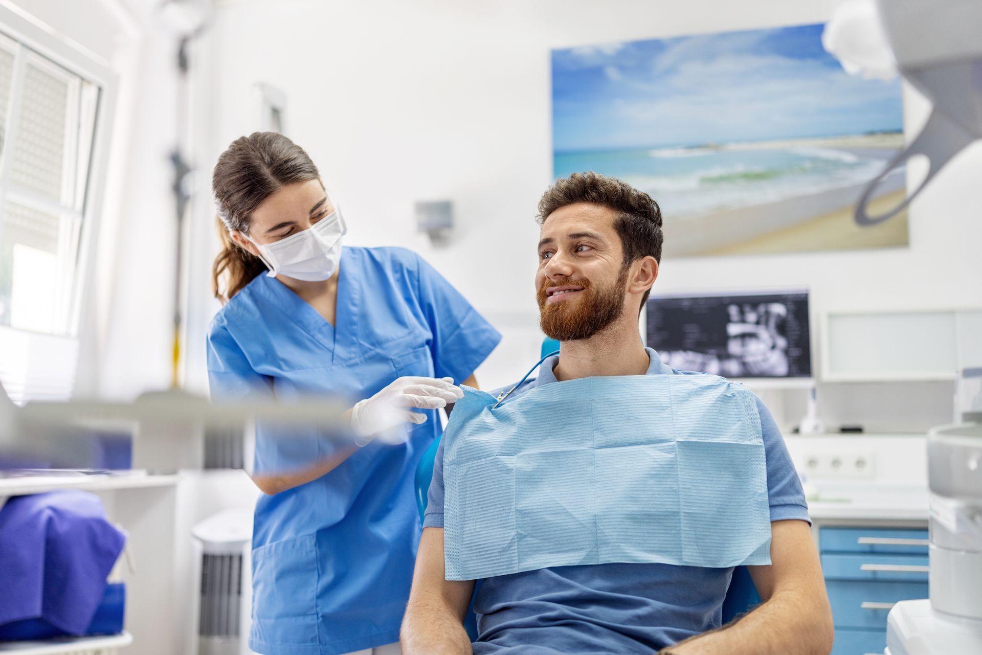 Dentist with smiling patient in modern dental clinic during exam prep.
