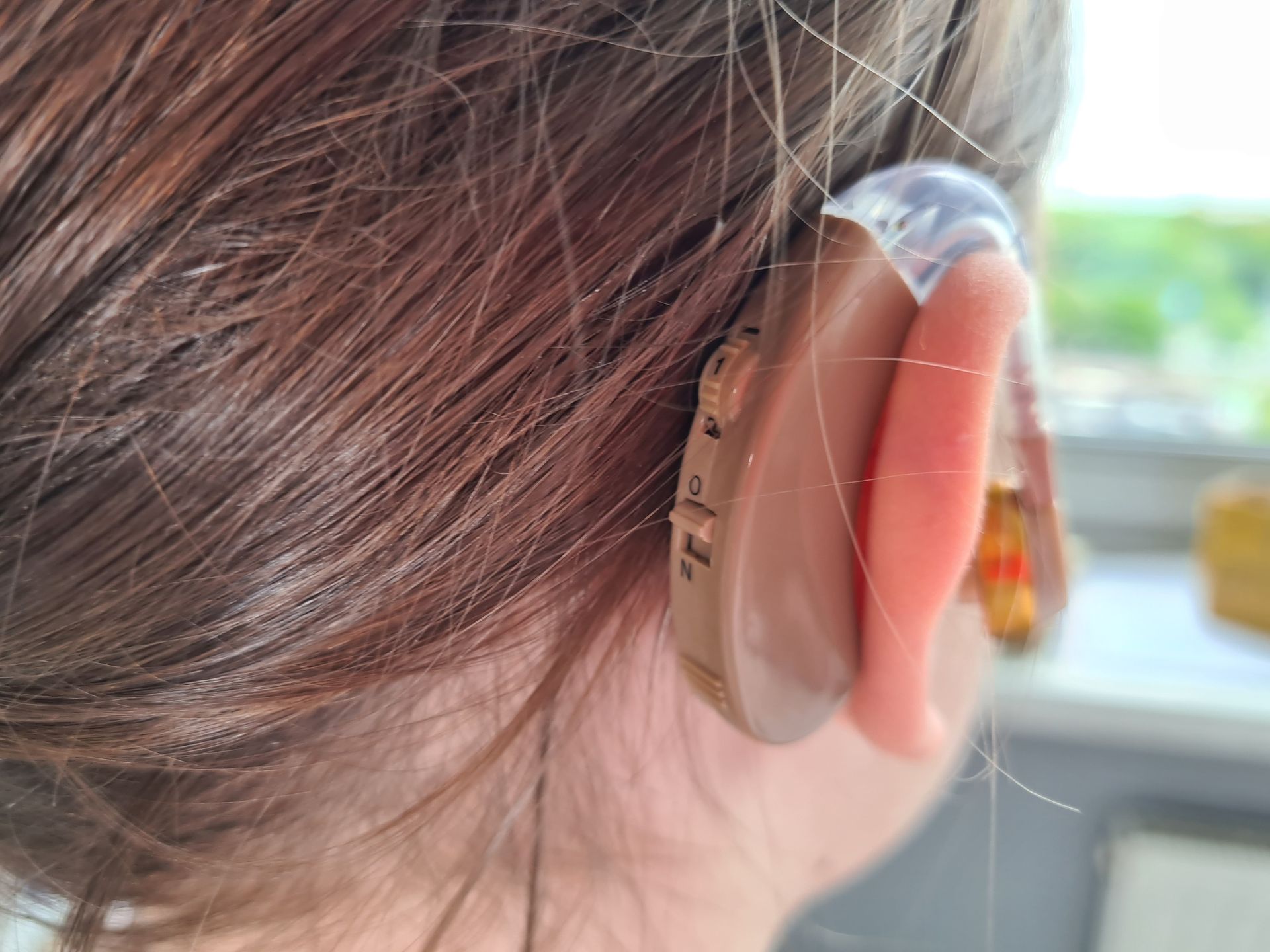 A woman wearing a hearing aid in her left ear.