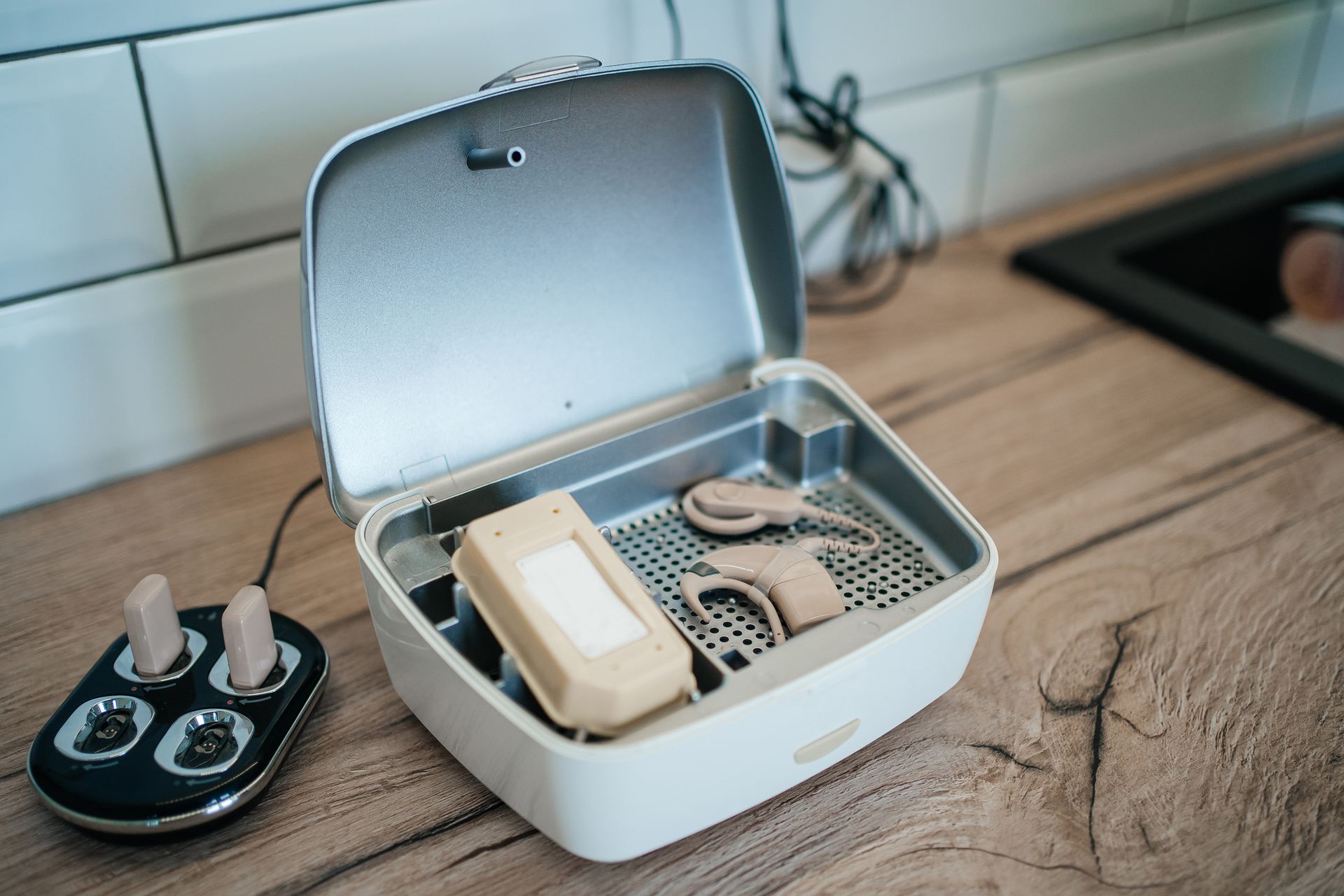 A box filled with hearing aids is sitting on a wooden table.