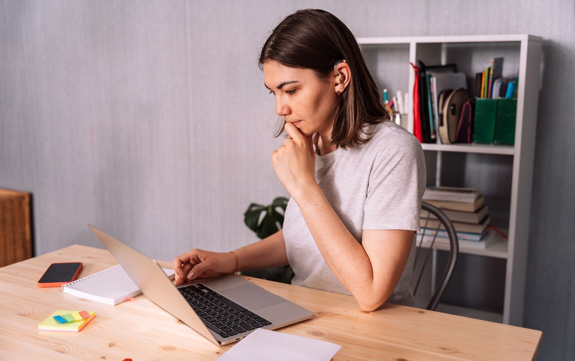 A woman is sitting at a desk using a laptop computer.