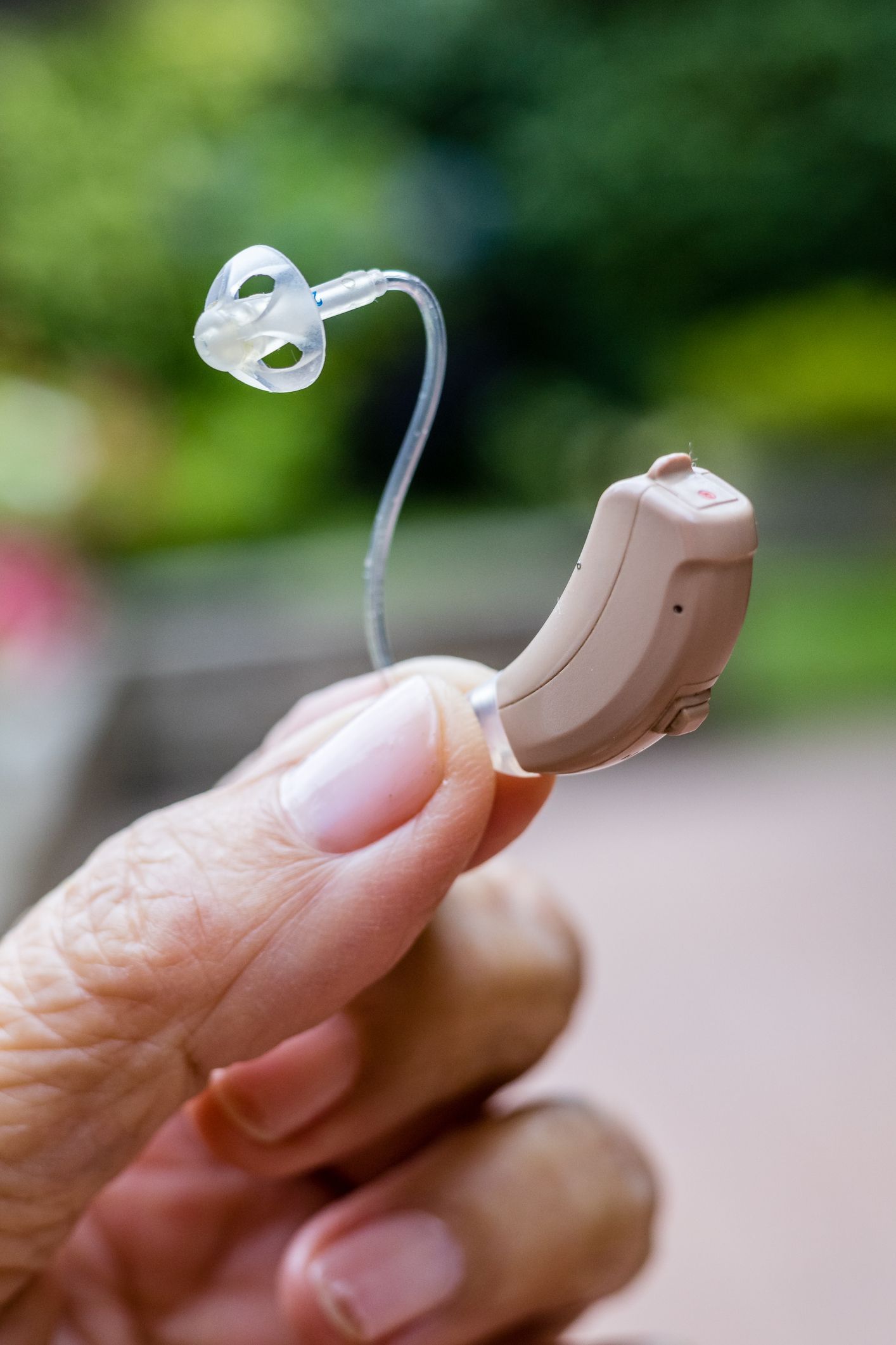 A person is holding a hearing aid in their hand.