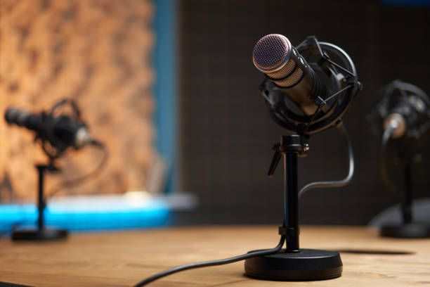 A microphone is sitting on a wooden table in a recording studio.