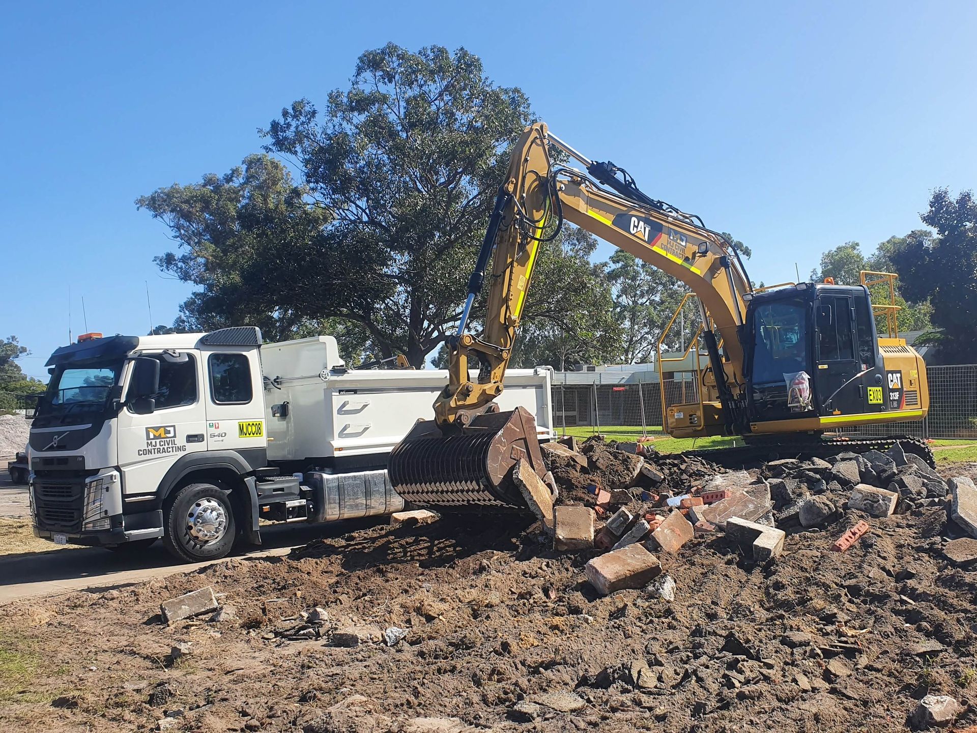 A yellow excavator is loading dirt into a dump truck.