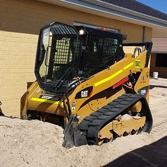 A bulldozer is sitting on top of a pile of sand in front of a building.