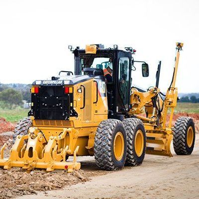 A yellow tractor is driving down a dirt road.