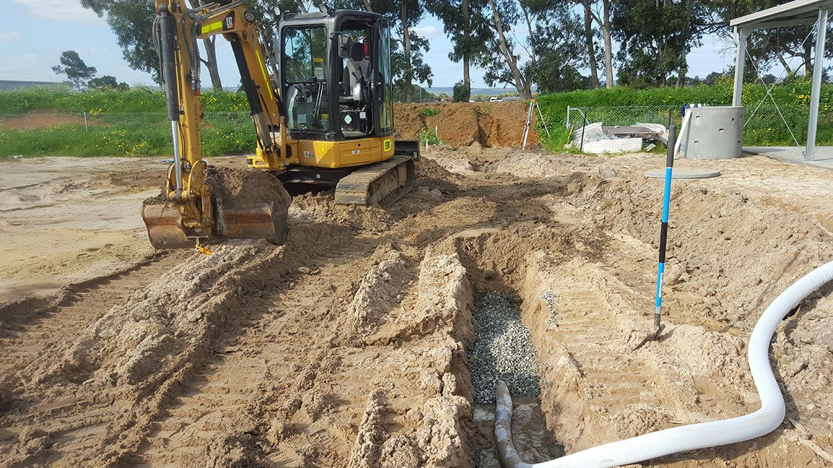 A yellow excavator is digging a hole in the dirt.