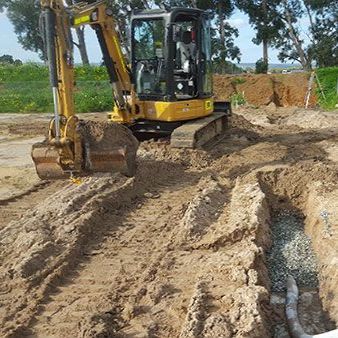 A yellow excavator is digging a hole in the dirt.