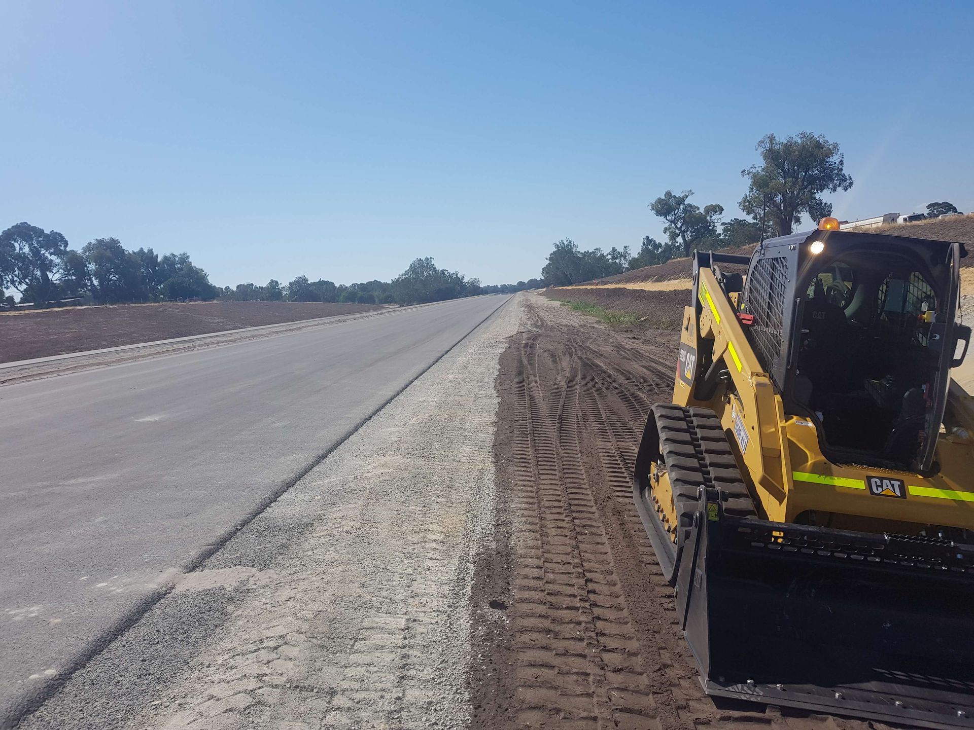 A yellow bulldozer is working on the side of a road.