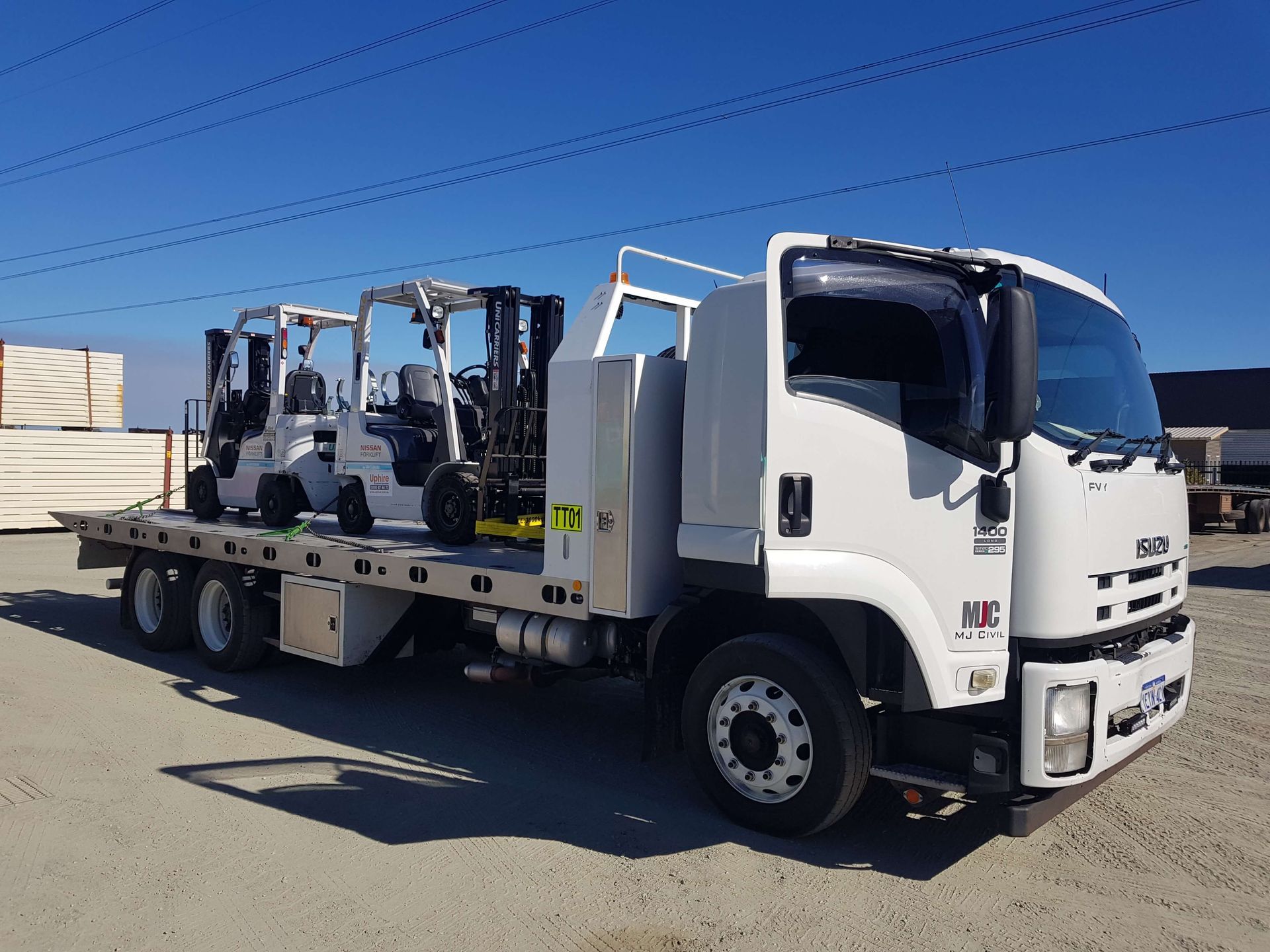 A white truck with forklifts on the back of it