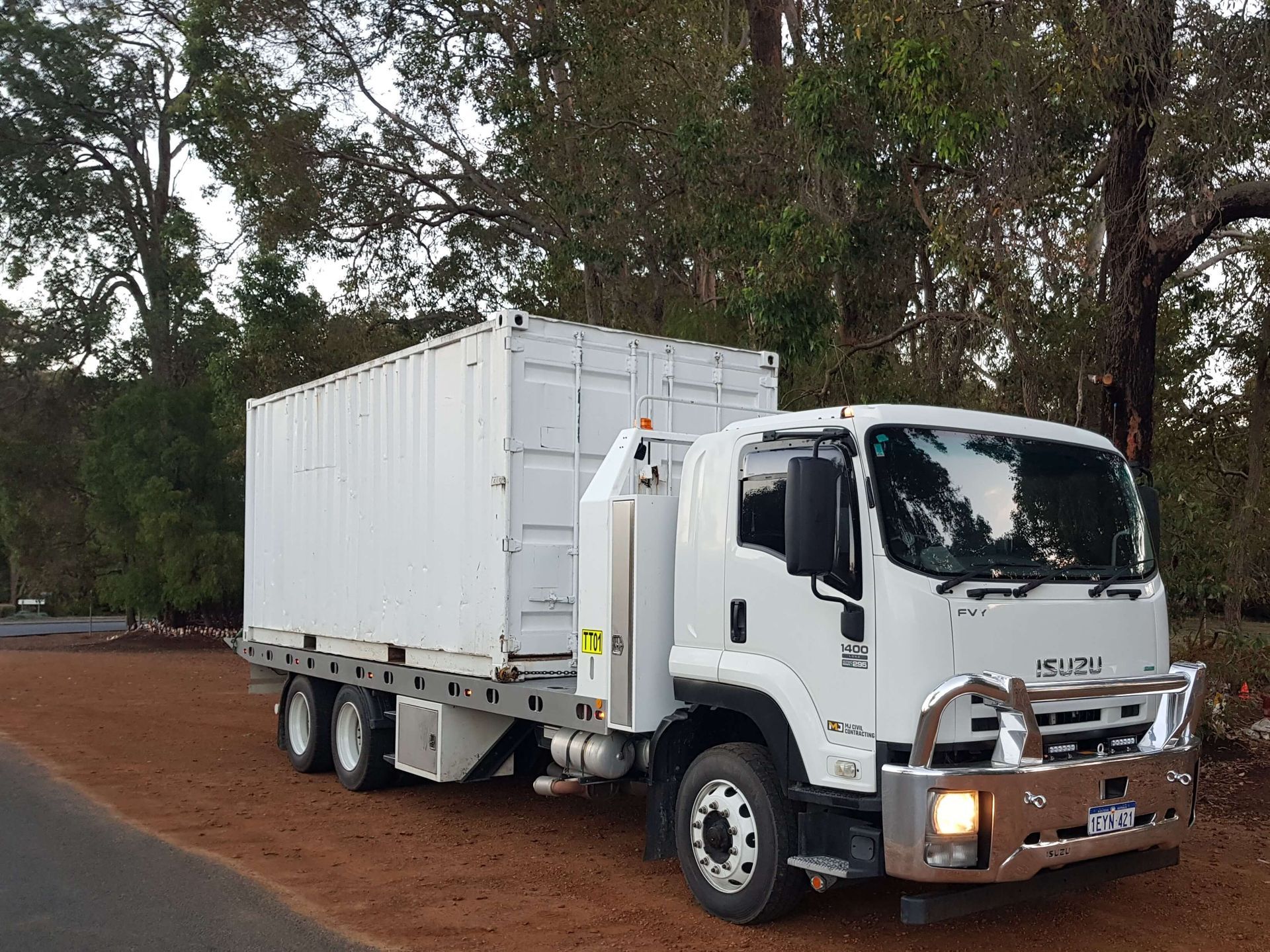 A white truck with a container on the back is parked on the side of the road.