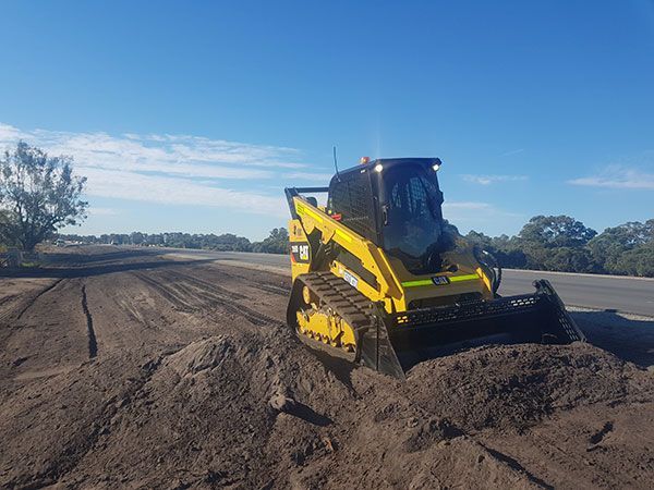 A yellow bulldozer is moving dirt on the side of a road.